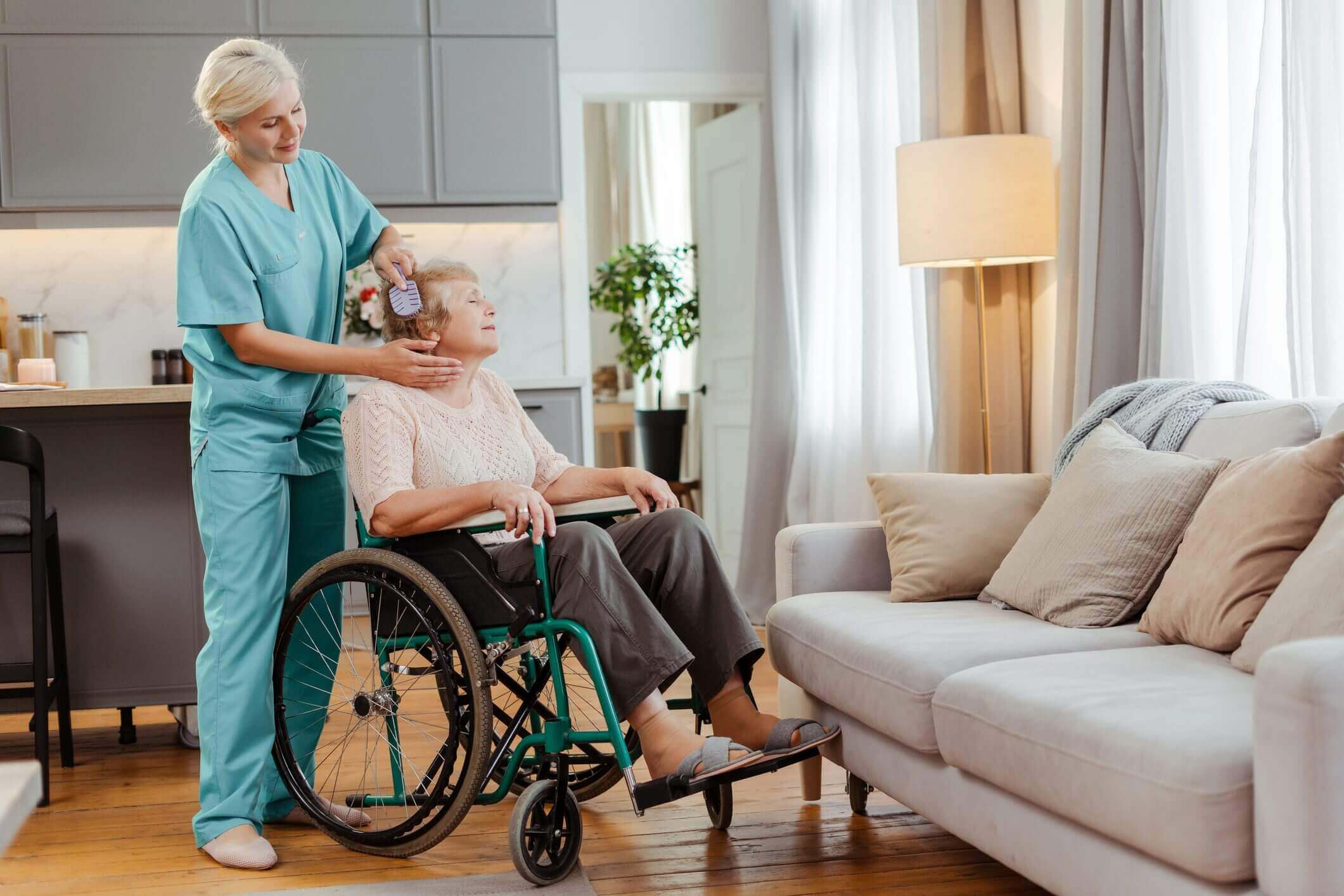 Caregiver assisting elderly woman in wheelchair.